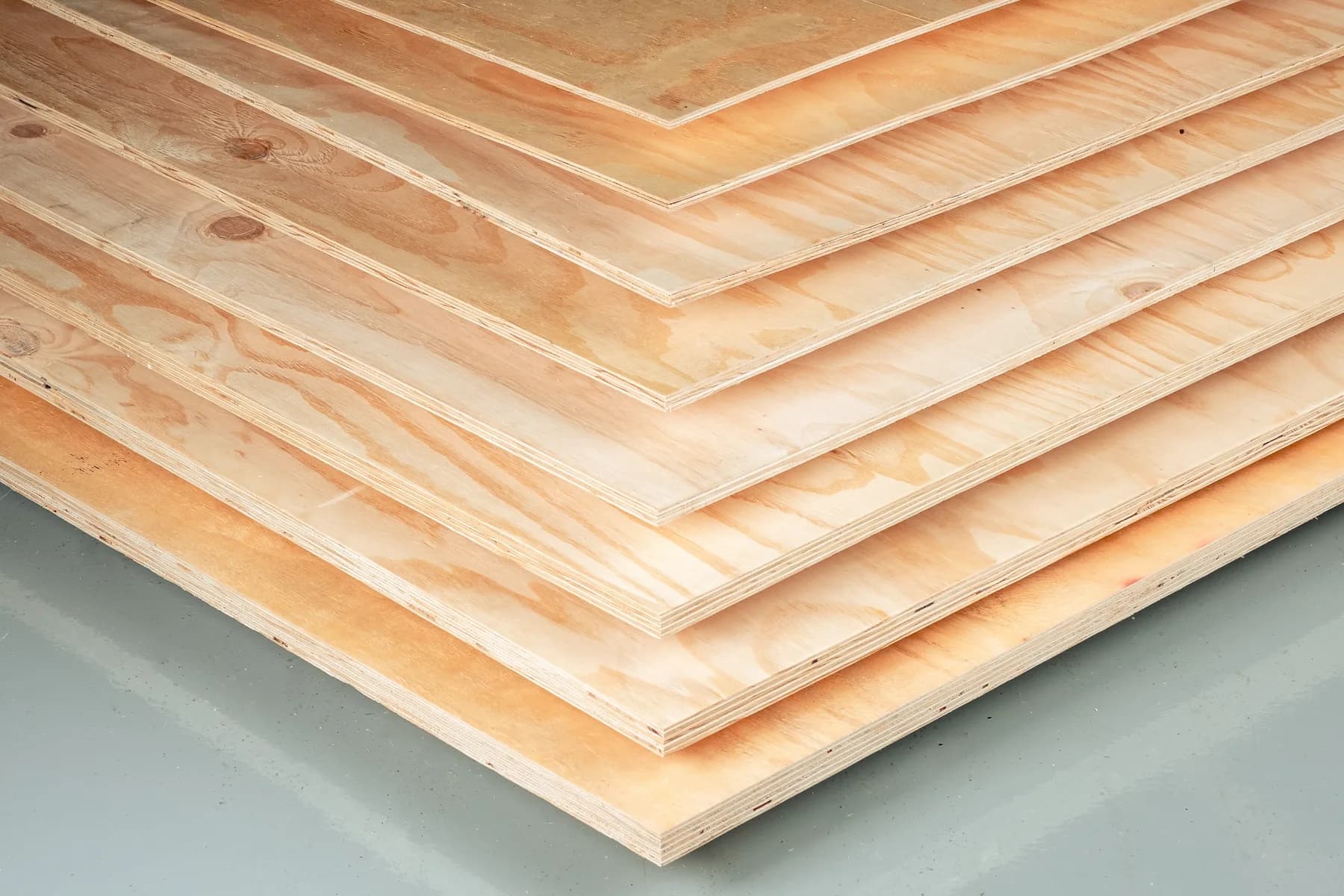 Pine plywood sheets fanned out, revealing the cross-laid veneers of each panel along the edge