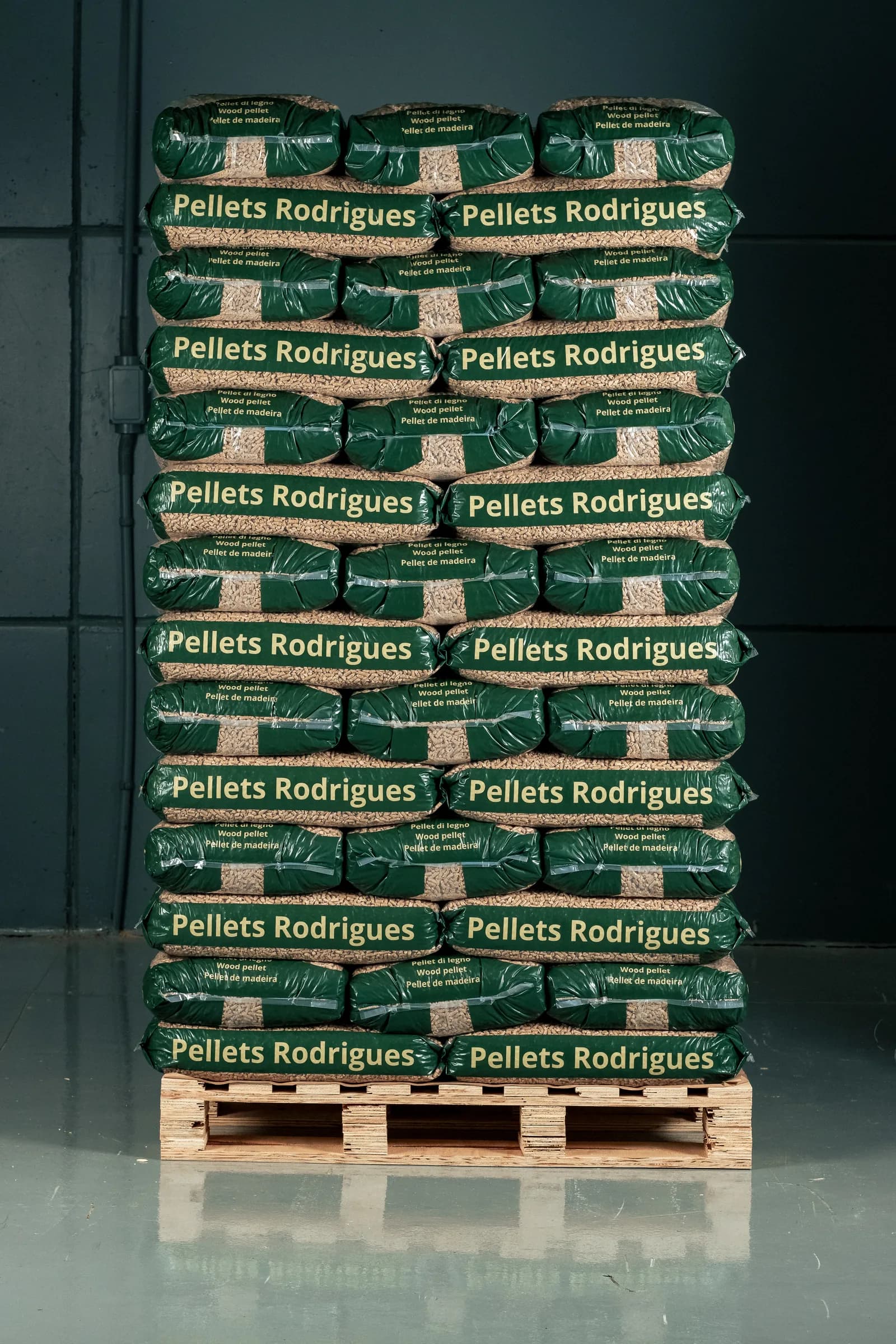 A tall pallet of 15 kg Pellets Rodrigues bags stacked in a warehouse