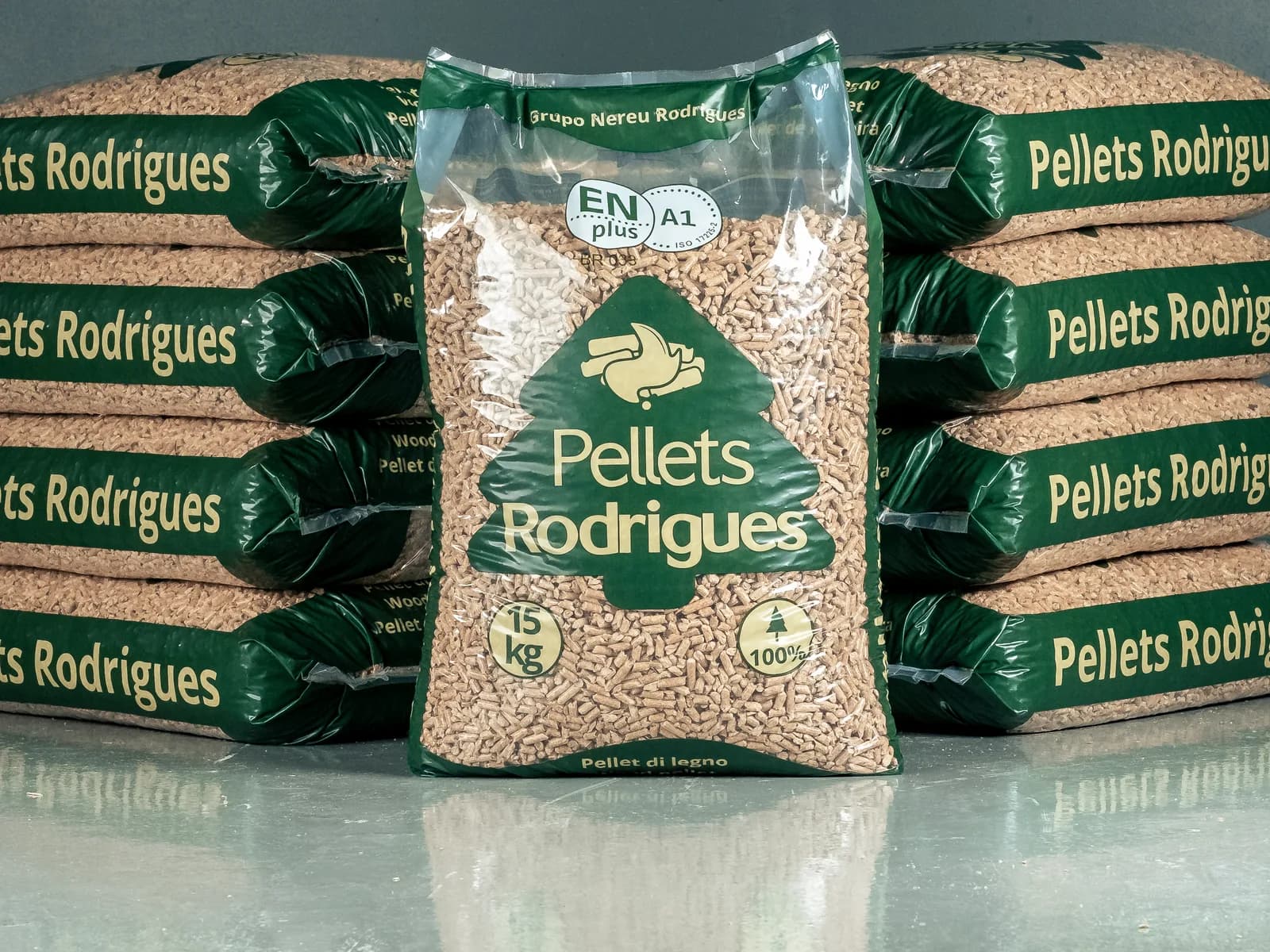 A 15 kg bag of Pellets Rodrigues standing upright, with the ENplus A1 seal, between two stacks of bags